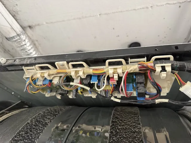 Underside of a dryer control panel showing the control board and its wiring harness